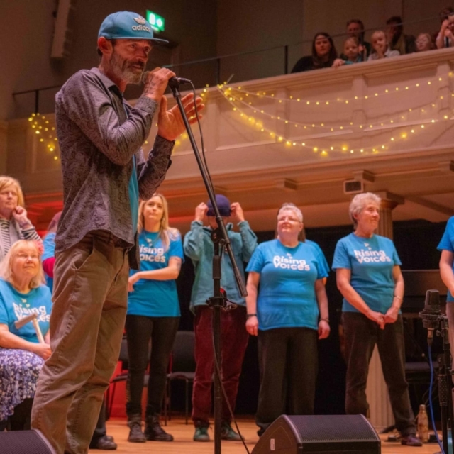 A choir member introducing a song with the choir standing around them at the High Sheriff concert in 2024 at St George's