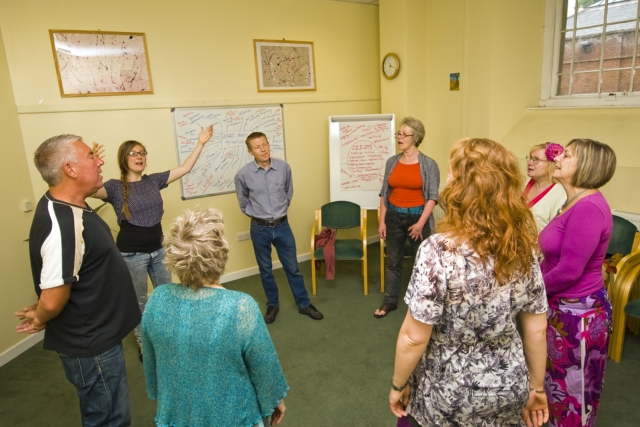 Rising Voices standing in a circle rehearsing inside Brunswick Court before their first performance.