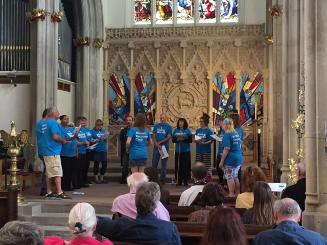 The choir standing in a semi-circle, performing in a church in 2016