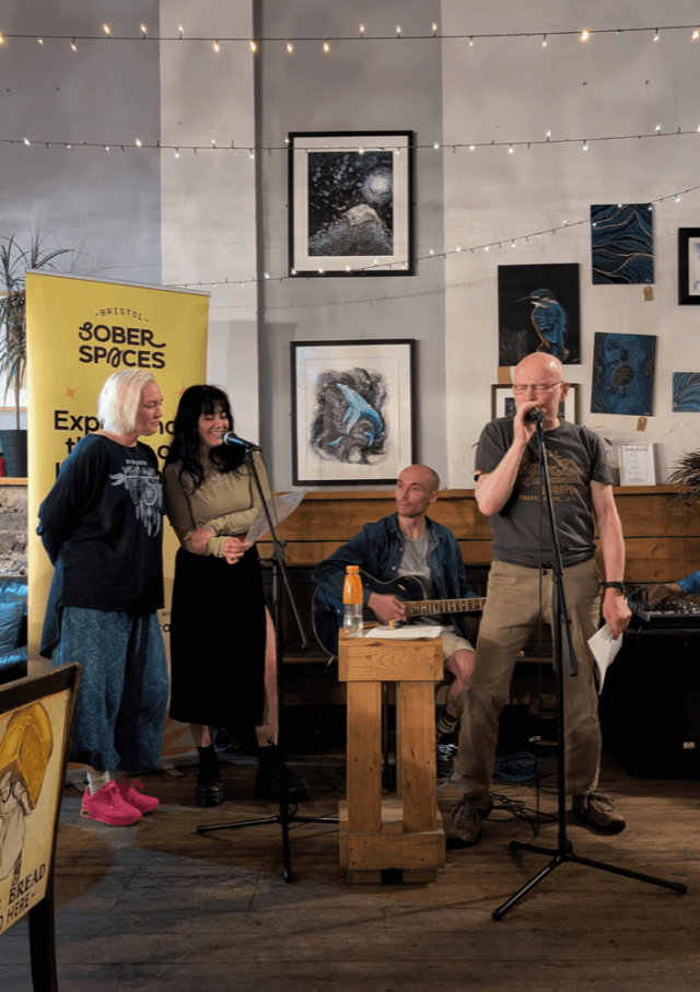 A singer and guitar player performing at the Bristol Sober Spaces open mic at The Orchard