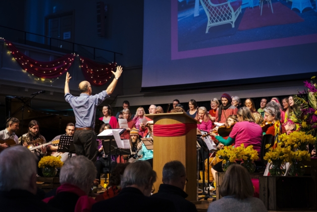 The choir and orchestra performing together on stage at St George's for Maggie's memorial, led by Jon James