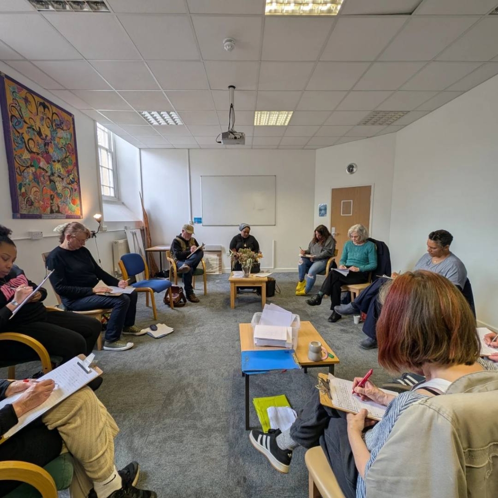 The creative writing group sitting together in a circle and writing during a task