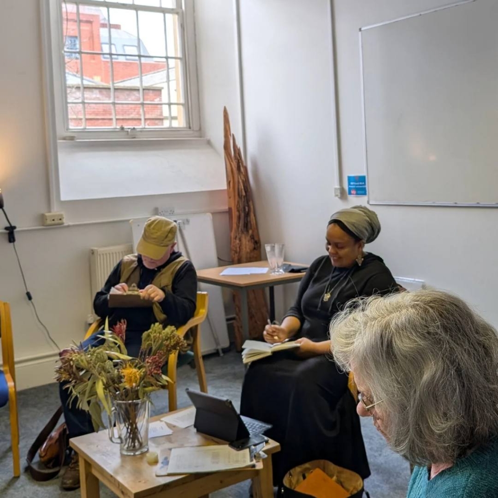 Sukina Noor sitting in a circle with the Creative Writing group as everyone writes during a task